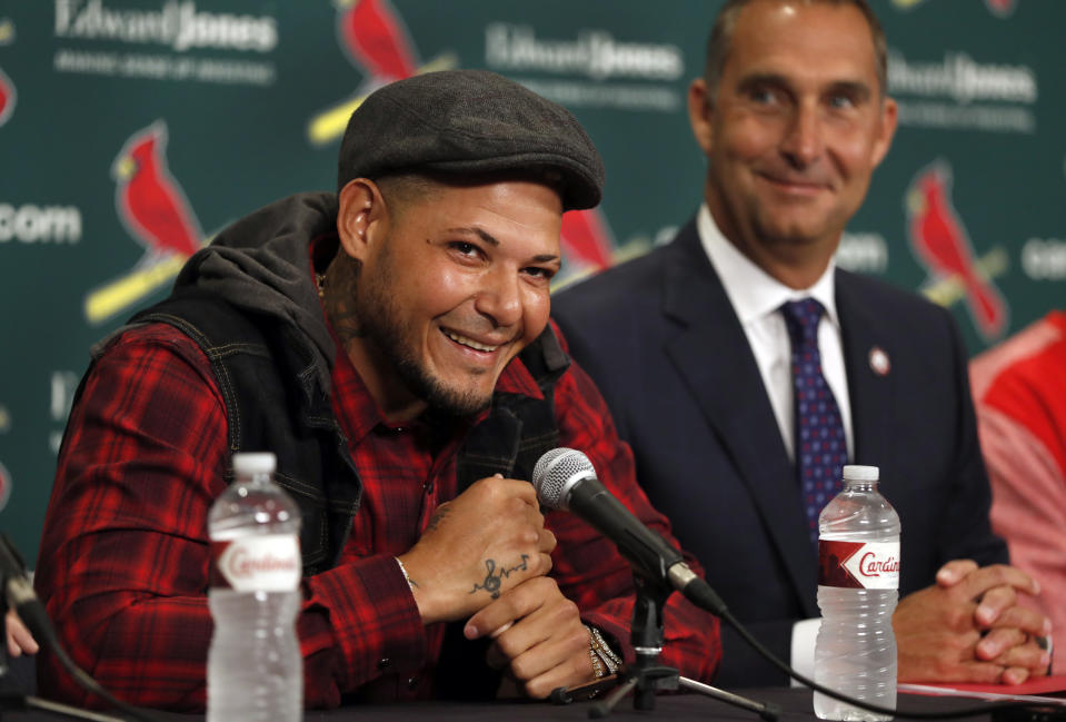 St. Louis Cardinals catcher Yadier Molina, left, smiles alongside Cardinals general manager John Mozeliak, right, during a news conference ahead of a baseball game against the Chicago Cubs, Sunday, April 2, 2017, in St. Louis. The Cardinals have finalized a contract extension with seven-time All-Star Molina that runs through the 2020 season. (AP Photo/Jeff Roberson)