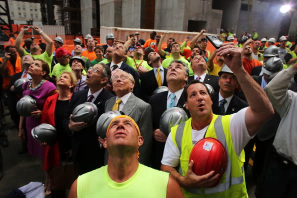 With developer Larry Silverstein (yellow tie) behind him, construction worker Frank Gasior (C) watches as the last steel beam, signed by members of the crews that helped build the tower, is hoisted 977 feet to the top of Four World Trade Center on June 25, 2012 in New York City. The trapezoidal glass and steel office building, which is designed as an architectural backdrop to the September 11 Memorial, is scheduled to open in 2013. (Photo by Spencer Platt/Getty Images)