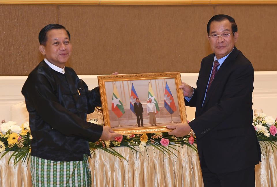 In this photo provided by An Khoun Sam Aun/National Television of Cambodia, Cambodian Prime Minister Hun Sen, right, and Myanmar State Administration Council Chairman, Senior General Min Aung Hlaing, left, hold a souvenir photo showing them, after a meeting in Naypyitaw, Myanmar, Friday Jan. 7, 2022. Cambodian Prime Minister Hun Sen's visit to Myanmar seeking to revive peace efforts after last year's military takeover has provoked an angry backlash among critics, who say he is legitimizing the army's seizure of power. (An Khoun SamAun/National Television of Cambodia via AP)