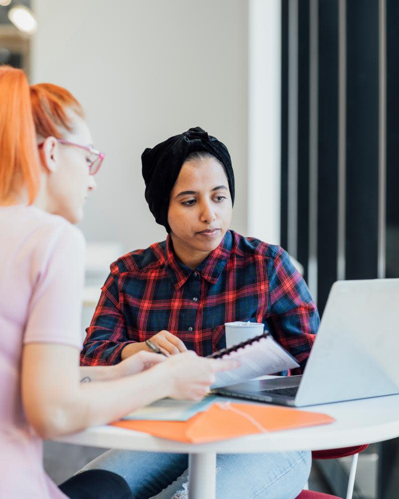 Young women sitting at a table working together with a laptop open in front of them.