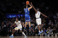 Xavier's Desmond Claude, center, shoots against Marquette's Kam Jones, right, in the first half of an NCAA college basketball game for the championship of the Big East men's tournament, Saturday, March 11, 2023, in New York. (AP Photo/John Minchillo)