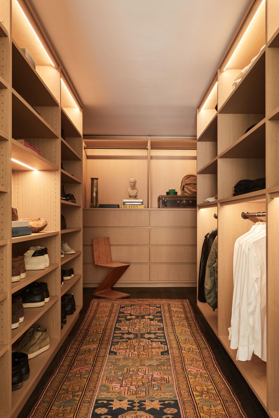 A few pieces of furniture and accessories—such as the Zig Zag chair by Gerrit Rietveld, the cast bronze vase by Rick Owens, the cast marble bust of a man, and the vintage Isfahan Persian handmade wool and silk rug—adorn the walk-in closet, making it both functional and stylish.