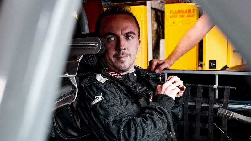 A photo of actor Frankie Muniz in the drivers seat of a race car. 