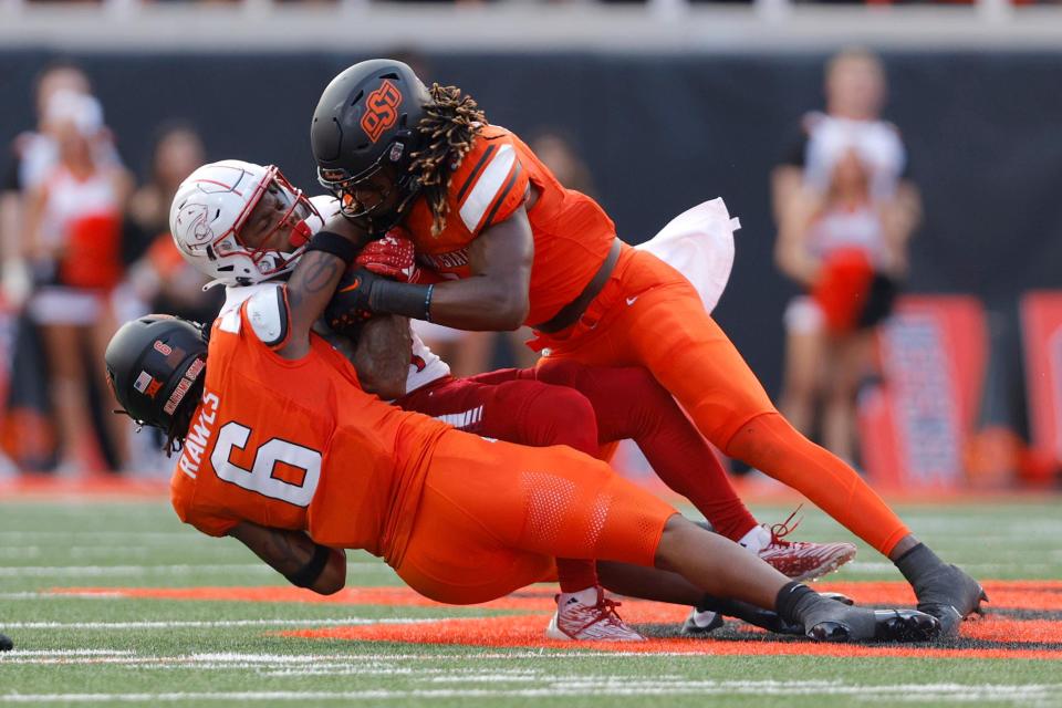 Oklahoma State's Lyrik Rawls (6) and Kendal Daniels (5) bring down South Alabama wide receiver Caullin Lacy during Saturday's game at Boone Pickens Stadium in Stillwater.