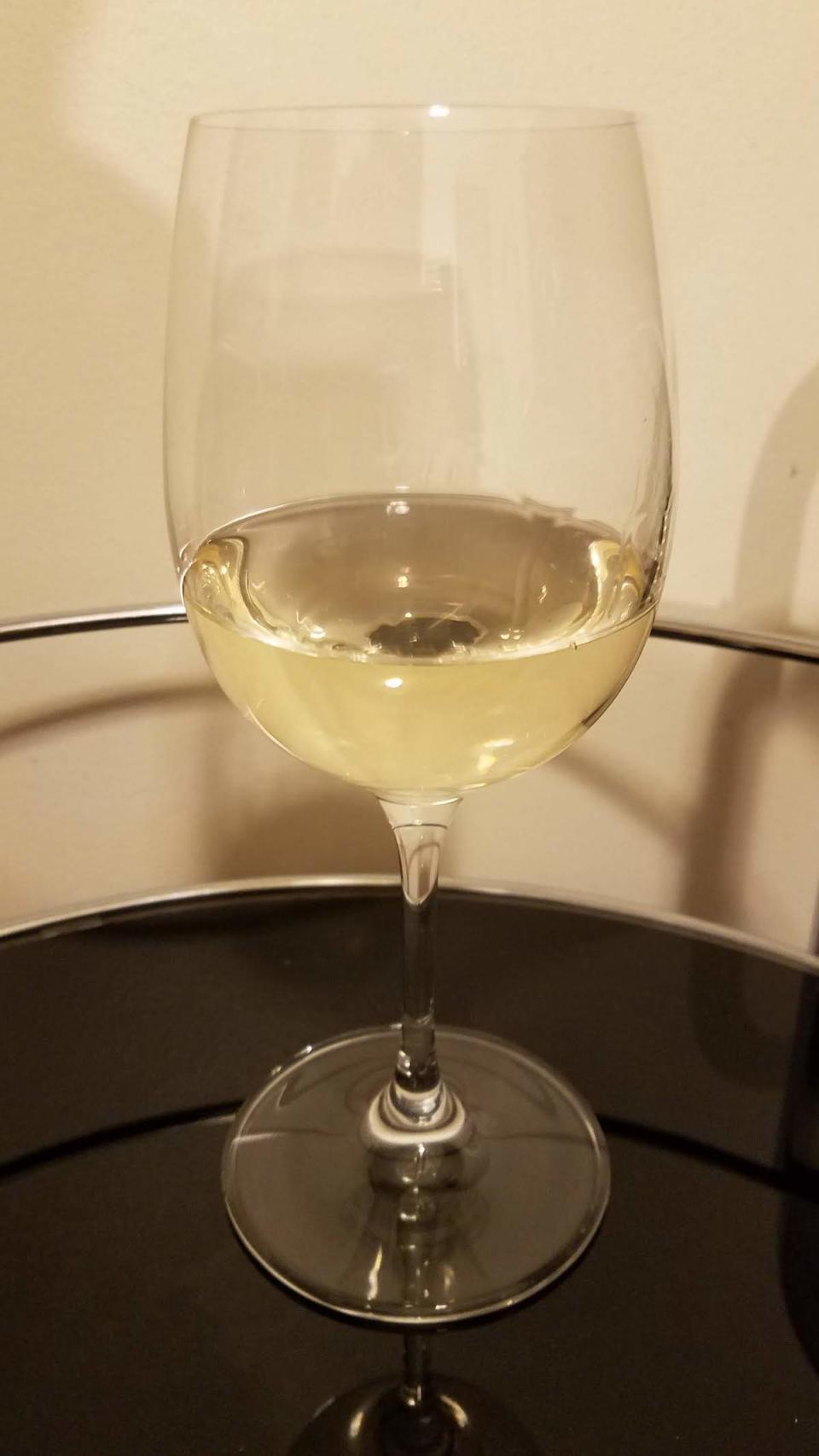 A glass of white wine on a black serving cart