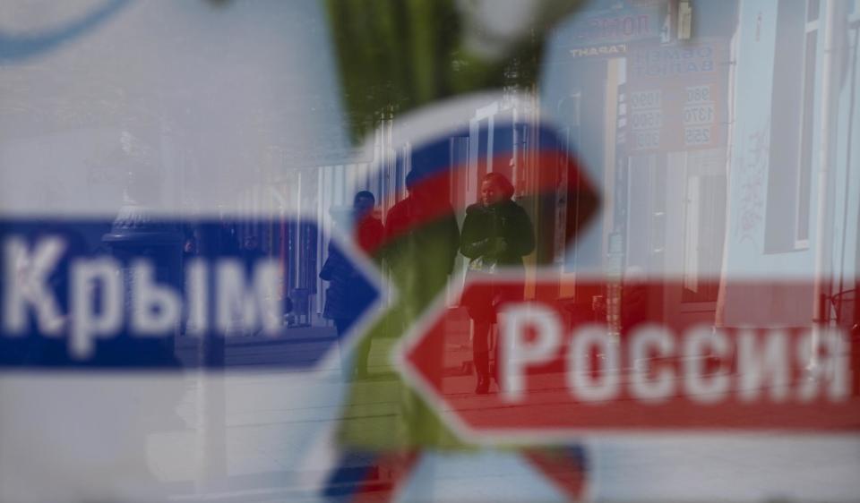 A couple's image reflected on an advertising board reading 'Russia, Crimea', on a street in Simferopol, Ukraine, on Monday, March 17, 2014. Ukraine's Crimean peninsula declared itself independent Monday after its residents voted overwhelmingly to secede and join Russia, while the United States and the European Union slapped sanctions against some of those who promoted the divisive referendum. (AP Photo/Ivan Sekretarev)