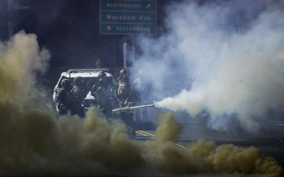 Gas-masked police using a large device to pump clouds of tear gas - Lindsey Wasson/Reuters