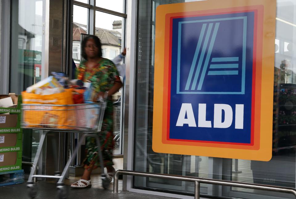 A woman pushes a shopping trolley past an Aldi logo. Source: Getty Images