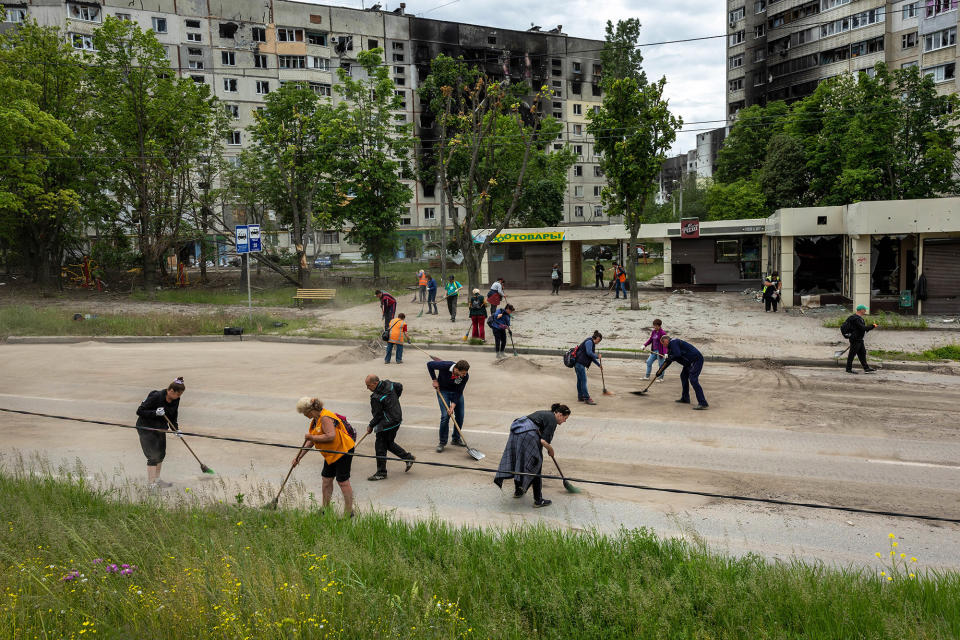 Public transit workers sweep up shrapnel and war debris in a former frontline neighborhood in Kharkiv, Ukraine, on May 25, 2022.