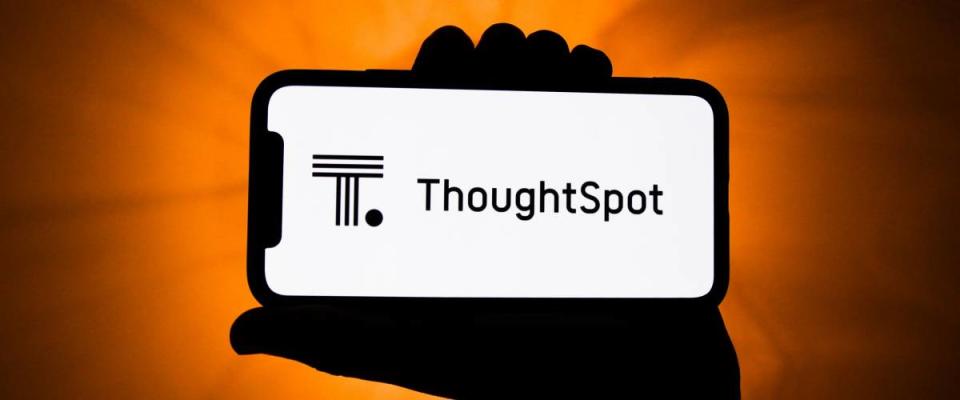 Hand holding up phone with ThoughtSpot logo on it.