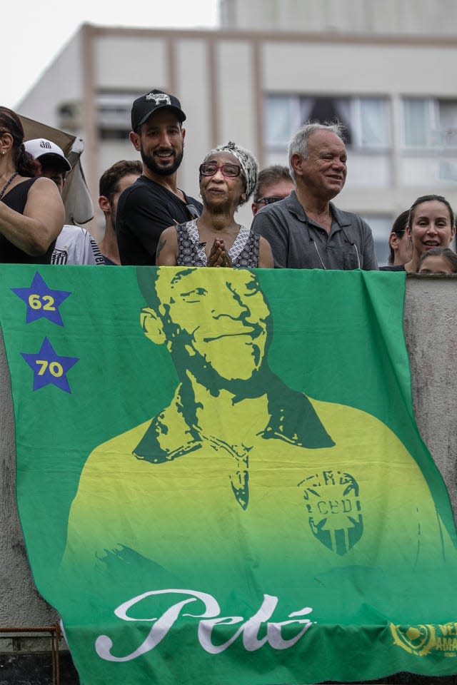 Maria Lucia Nascimento, the sister of the late Brazilian soccer great Pele, watches her brother’s funeral procession from their mother’s home