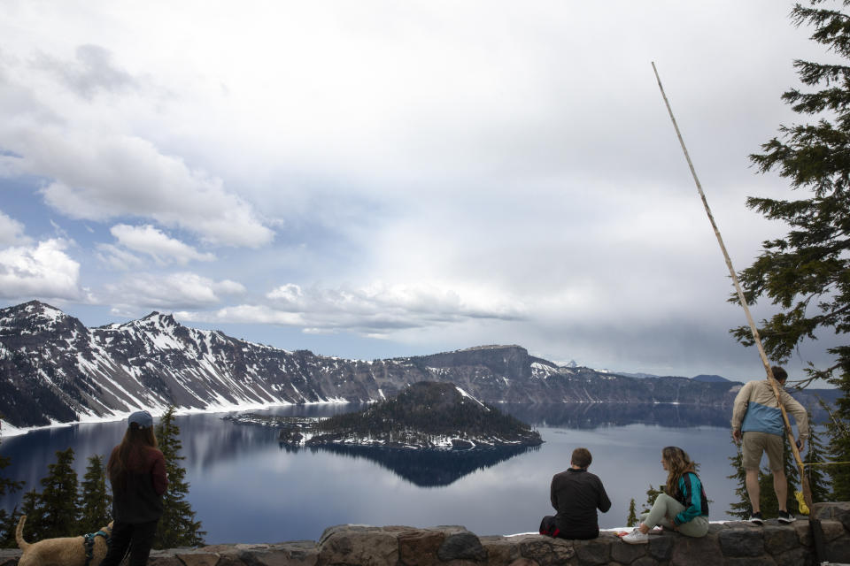 People visit Crater Lake on June 1, 2023, in Crater Lake, Ore. Management issues at Oregon's Crater Lake have prompted the federal government to consider terminating its contract with the national park's concessionaire. Crater Lake Hospitality is a subsidiary of Philadelphia-based Aramark and is contracted through 2030 to run concessions such as food and lodging. (AP Photo/Jenny Kane)