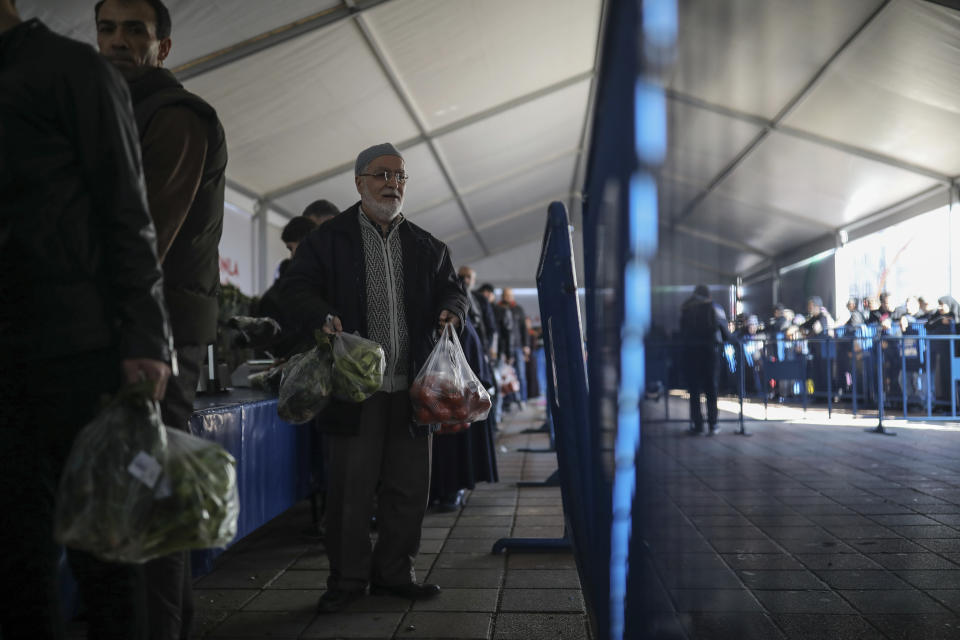 In this Sunday, Feb. 17, 2019 photo, a shopper stands after buying groceries at a government-run market selling spinach, tomatoes and peppers at discounted prices in an Istanbul neighbourhood. Turkey's President Recep Tayyip Erdogan's government has set up dozens of these temporary stalls in Turkey's largest cities in a bid to mitigate the effects of soaring food prices that have stung households. (AP Photo/Emrah Gurel)