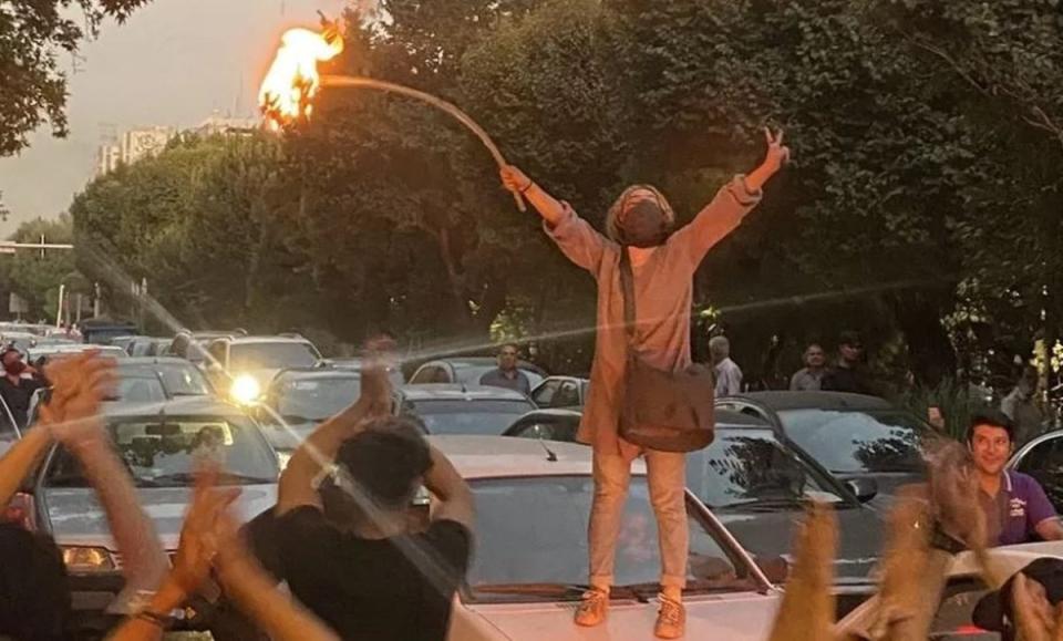 A woman set fire to her headscarf during a protest in Tehran (NA)