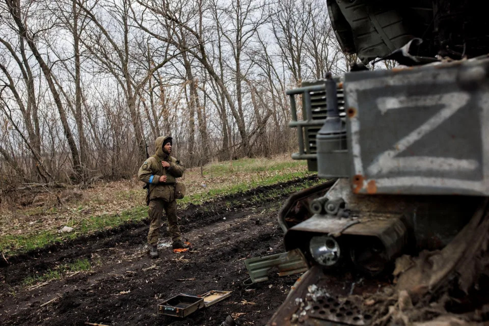 Ukrainian soldier standing next to a destroyed Russian military vehicle in Kharkiv