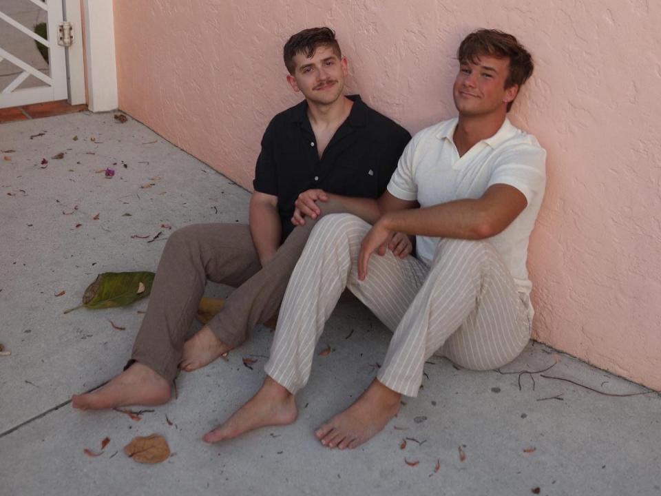 Tyler Tyner-Dernulc, left, and Noah Tyner-Dernulc, right, sit on the ground.