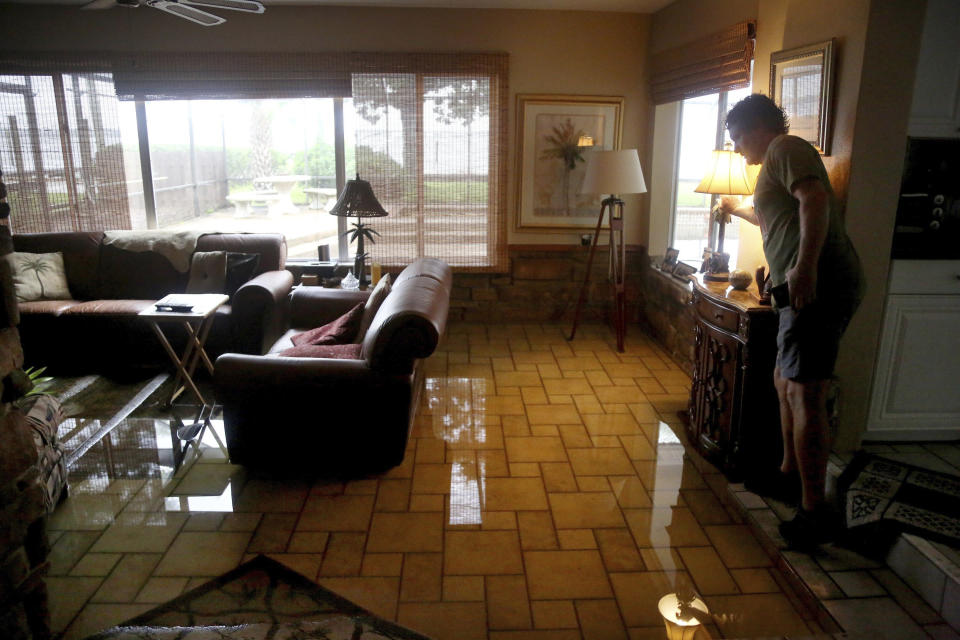 Leland Holland, of Oldsmar, Fla., inspects the flooded living room of his neighbor, Troy Shiltz, which was flooded overnight Thursday, Nov. 12, 2020, in the aftermath of Tropical Storm Eta. Eta dumped torrents of blustery rain on Florida's west coast as it moved over Florida after making landfall north of the heavily populated Tampa Bay area Thursday morning. (Douglas R. Clifford/Tampa Bay Times via AP)