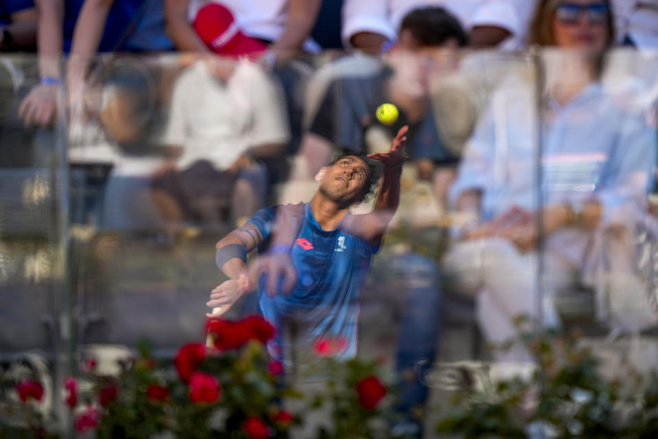 Chile's Alejandro Tabilo, reflected in a glass separation panel, serves to Germany's Alexander Zverev during a men's tennis semifinal match at the Italian Open tennis tournament, in Rome, Friday, May 17, 2024. (AP Photo/Andrew Medichini)