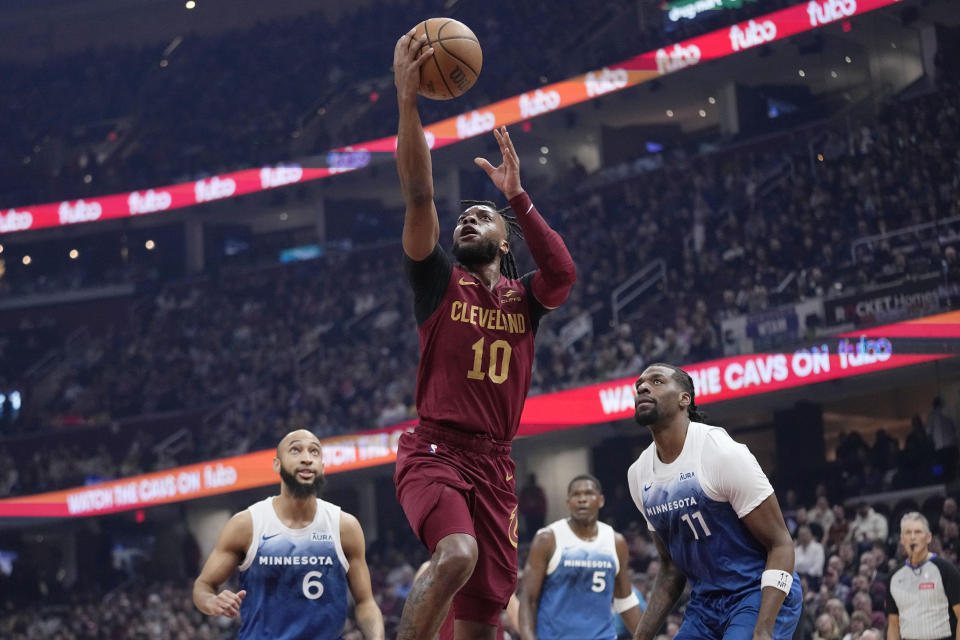 Cleveland Cavaliers guard Darius Garland (10) shoots as Minnesota Timberwolves guard Jordan McLaughlin (6), guard Anthony Edwards (5) and center Naz Reid (11) watch during the first half of an NBA basketball game Friday, March 8, 2024, in Cleveland. (AP Photo/Sue Ogrocki)