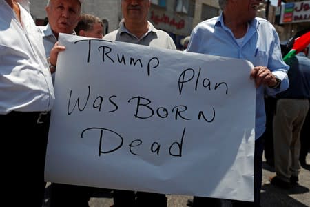 Palestinians hold a sign during a protest against the U.S.-led economic workshop for Mideast plan, in Ramallah in the Israeli occupied West Bank