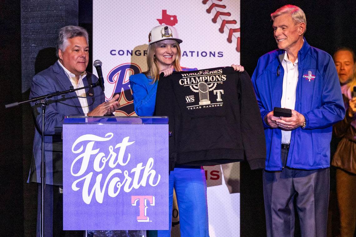 Texas Rangers President Neil Leibman, left, and Owner Ray Davis, right, gift a World Series hat and shirt to Fort Worth Mayor Mattie Parker on her birthday for the World Series celebration event at Billy Bob’s Texas in Fort Worth on Thursday, Nov. 9, 2023. Chris Torres/ctorres@star-telegram.com