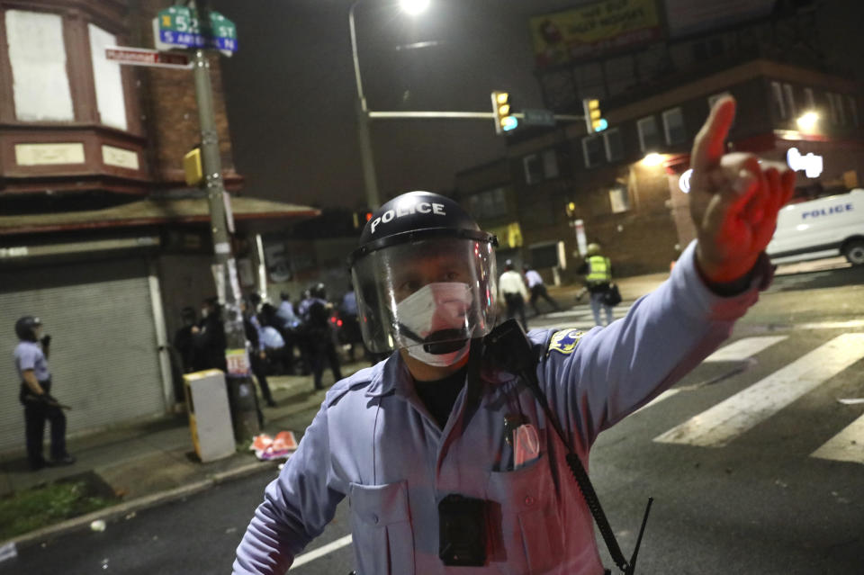 Police order an Inquirer photographer to move back as they detain protesters along 52nd Street in West Philadelphia in the early hours of Tuesday, Oct. 27, 2020. Protesters gathered after police shot and killed a Black man in West Philadelphia on Monday. (Tim Tai/The Philadelphia Inquirer via AP)