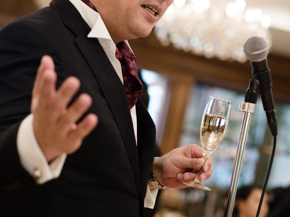 best man giving a speech at a wedding with champagne and a microphone