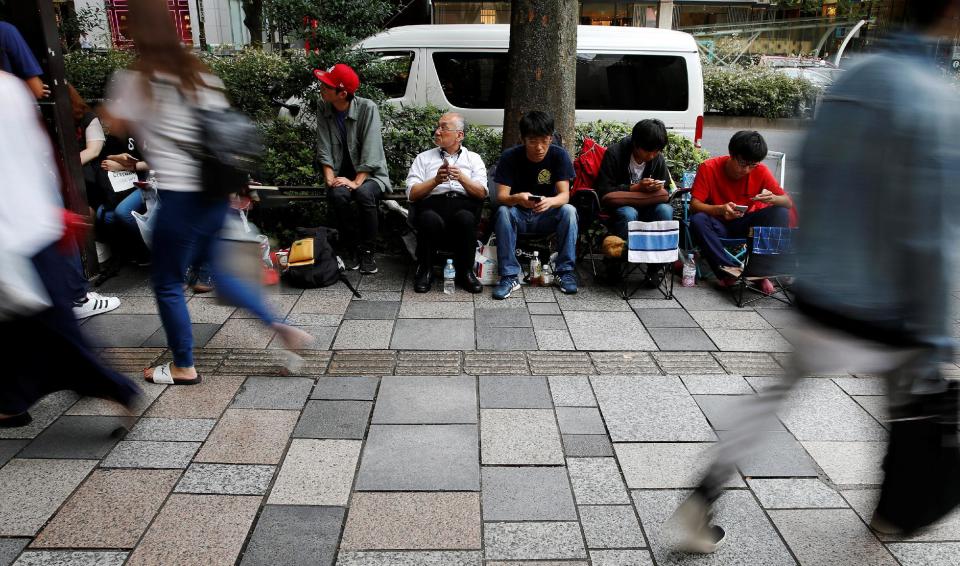 People sit in queue for the release of Apple's new iPhone 7 and 7 Plus in front of the Apple Store in Tokyo's Omotesando shopping district, Japan September 15, 2016. REUTERS/Toru Hanai