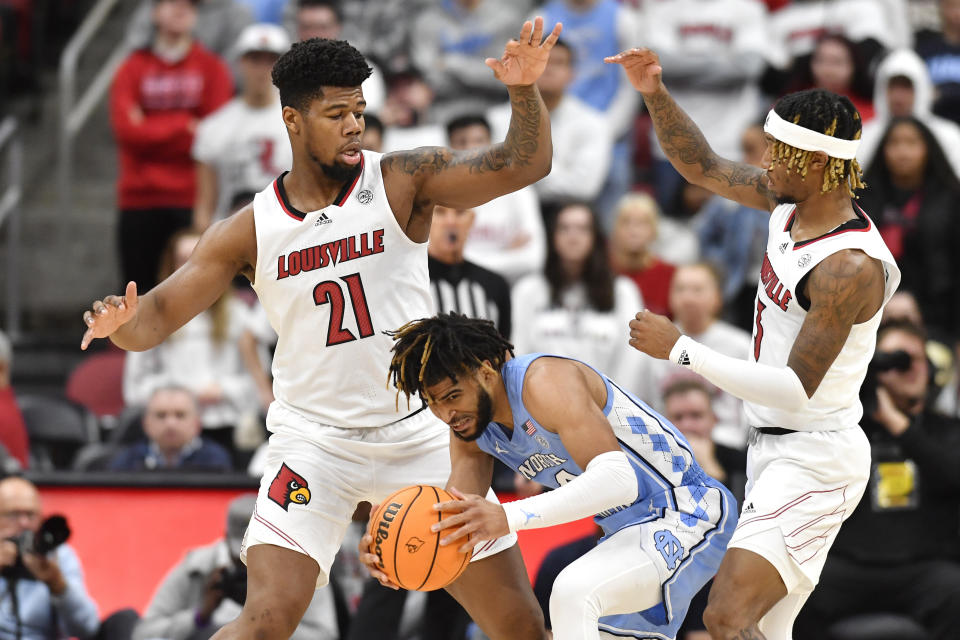 North Carolina guard R.J. Davis (4) is trapped by the defense of Louisville forward Sydney Curry (21) and guard El Ellis (3) during the second half of an NCAA college basketball game in Louisville, Ky., Saturday, Jan. 14, 2023. North Carolina won 80-59. (AP Photo/Timothy D. Easley)