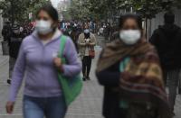People wearing protective face masks walk on a pedestrian walkway in downtown Lima, Peru, Wednesday, July 1, 2020. Major cities in Peru including the capital, will begin allowing for public transportation and certain businesses to reopen, but will still restrict the movement of the elderly and young children. (AP Photo/Martin Mejia)