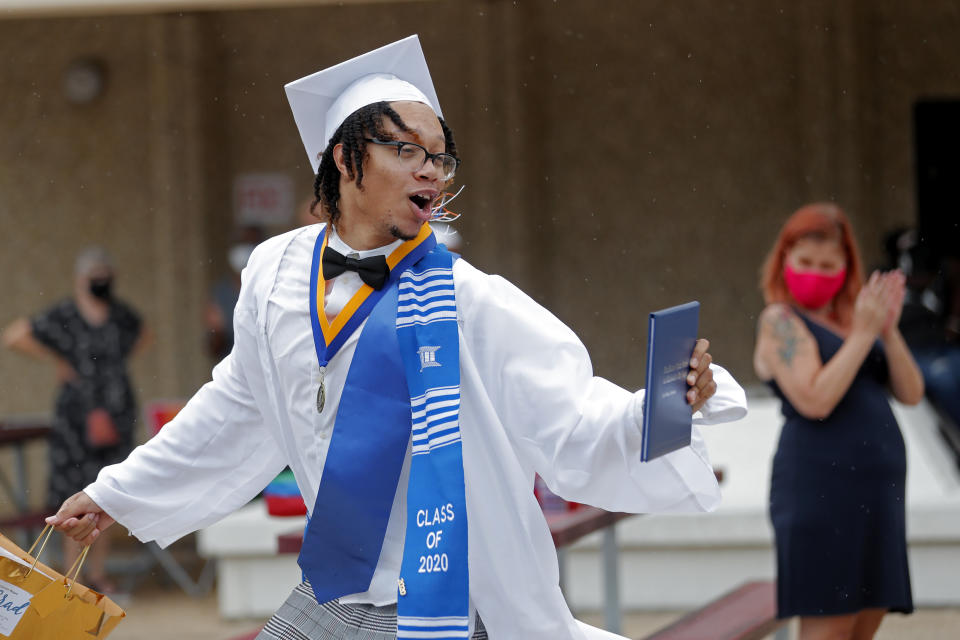 Graduate Cameron Magee of the New Orleans Charter Science and Math High School class of 2020 celebrates after receiving his diploma at a drive-in graduation ceremony as a result of the COVID-19 pandemic, outside Delgado Community College in New Orleans, Wednesday, May 27, 2020. Students and family got out of their cars to receive diplomas one by one, and then held a parade of cars through city streets. (AP Photo/Gerald Herbert)