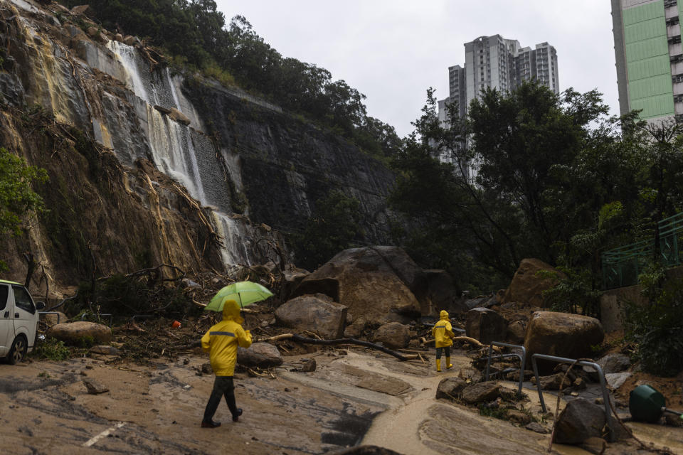 Workers walk through a landslide following heavy rainstorms in Hong Kong, Friday, Sept. 8, 2023. (AP Photo/Louise Delmotte)