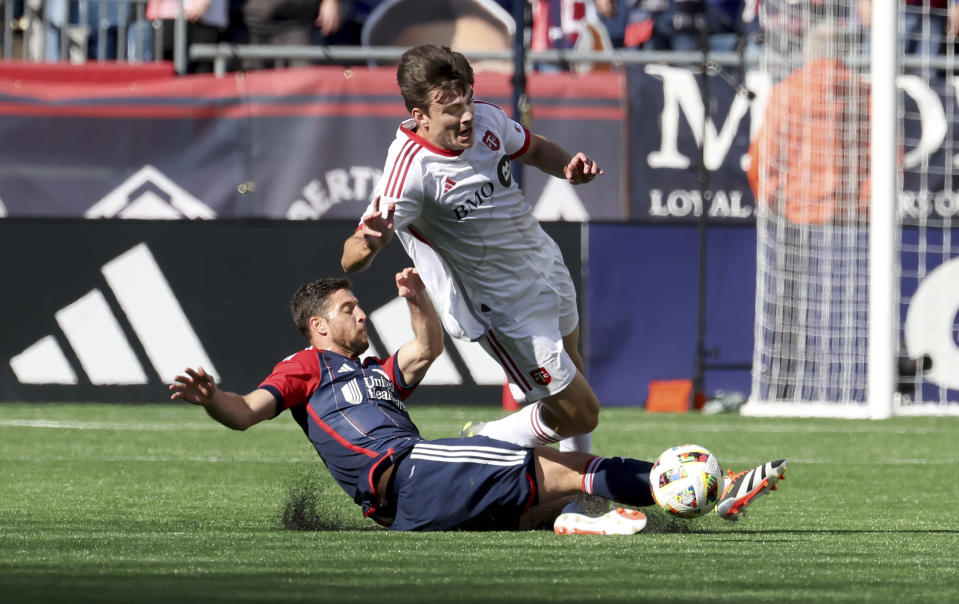 New England Revolution midfielder Matthew Polster, bottom, trips Toronto FC midfielder Alonso Coello, top, in the first half of an MLS soccer match Sunday, March 3, 2024, in Foxborough, Mass. (AP Photo/Mark Stockwell)