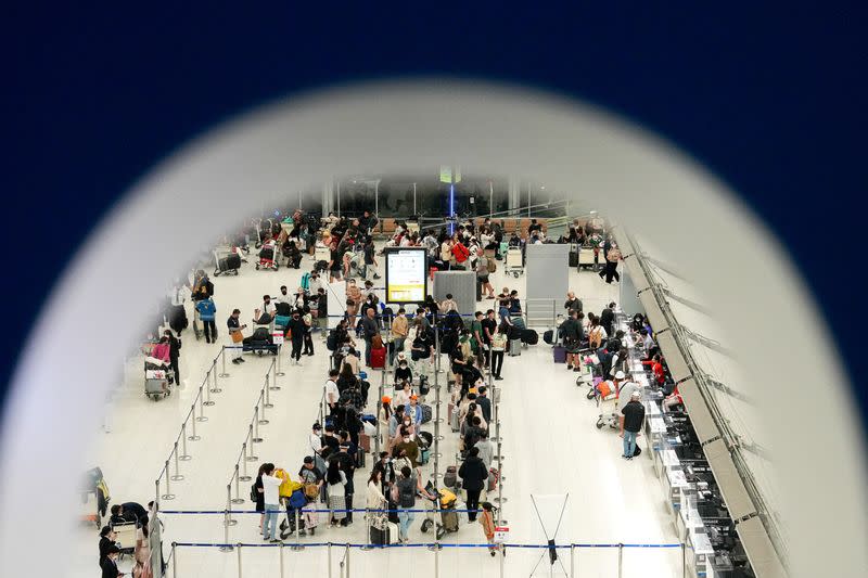 FILE PHOTO: Tourists wait to check in for flights at Bangkok's Suvarnabhumi airport