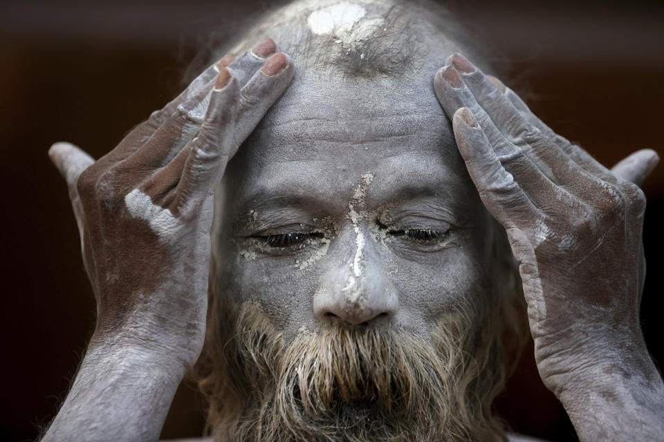 A Naga Sadhu or Naked Hindu holy man rubes ash as he prepares to take holy dips in the river Ganges during Shahi snan or a Royal bath during Kumbh mela, in Haridwar in the Indian state of Uttarakhand, Monday, April 12, 2021. As states across India are declaring some version of a lockdown to battle rising Covid cases as part of a nationwide second-wave, thousands of pilgrims are gathering on the banks of the river Ganga for the Hindu festival Kumbh Mela. The faithful believe that a dip in the waters of the Ganga will absolve them of their sins and deliver them from the cycle of birth and death. (AP Photo/Karma Sonam)