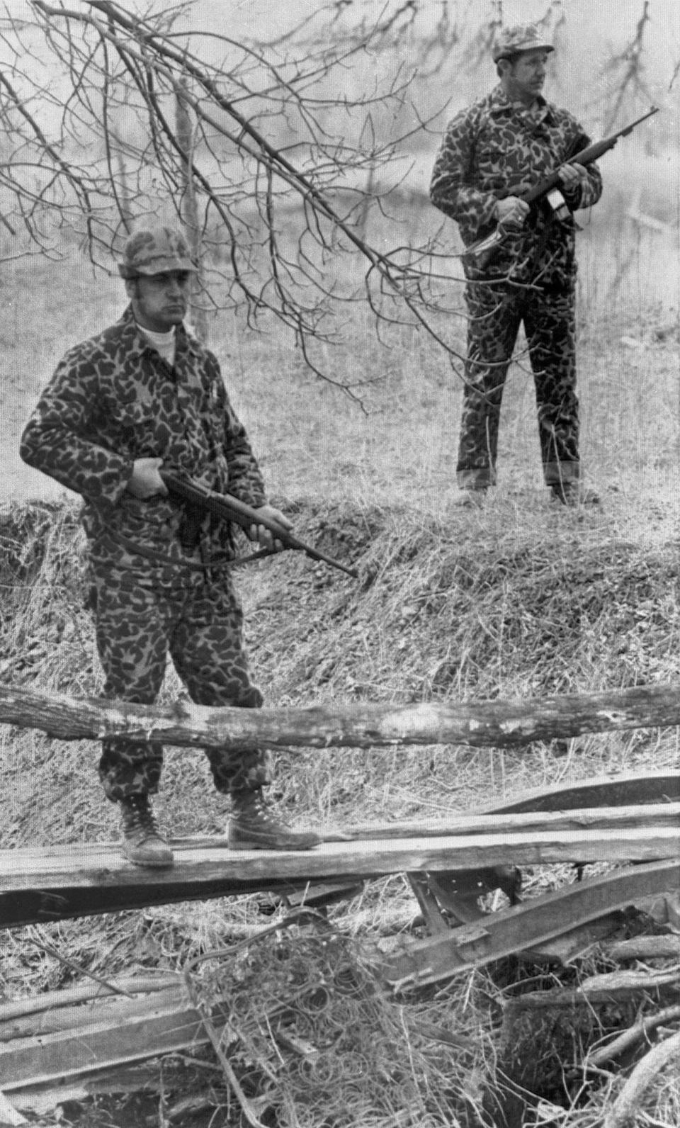 FILE - U.S. deputy marshals stand guard at a small creek that flows near their federal outpost at Wounded Knee, S.D., on March 31, 1973. The creek and its heavy trees and foliage has served as a route for people trying to leave or enter Wounded Knee. (AP Photo/Jim Mone, File)