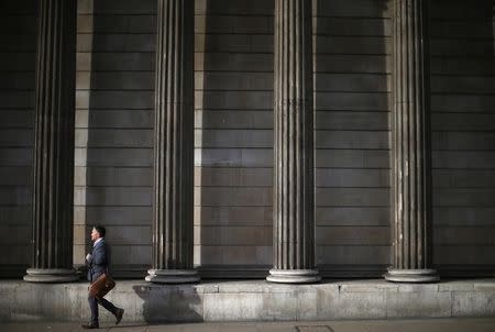 A man walks past the columns of the Bank of England in the city of London, October 17, 2014. REUTERS/Andrew Winning