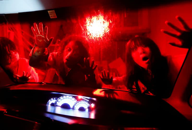 Actors dressed as zombies or ghouls perform during a drive-in haunted house show by Kowagarasetai, for people inside a car in order to maintain social distancing amid the spread of the coronavirus disease (COVID-19), in Tokyo