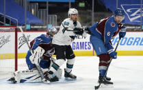 San Jose Sharks right wing Kevin Labanc, center, distracts Colorado Avalanche defenseman Erik Johnson, right, as the puck slips wide of the net past goaltender Philipp Grubauer during the second period of an NHL hockey game Tuesday, Jan. 26, 2021, in Denver. (AP Photo/David Zalubowski)