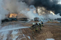 In this photo provided Saturday, March 6, 2021 by the Syrian Civil Defense group known as the White Helmets, Civil Defense workers extinguish burning oil tanker trucks after a suspected missile strike around the towns of Jarablus and al-Bab, near the border with Turkey, in western Aleppo province, Syria. Syrian opposition groups and the Syrian Observatory for Human Rights, based in Britain, blamed Russia for the Friday night strikes. (Syrian Civil Defense White Helmets via AP)