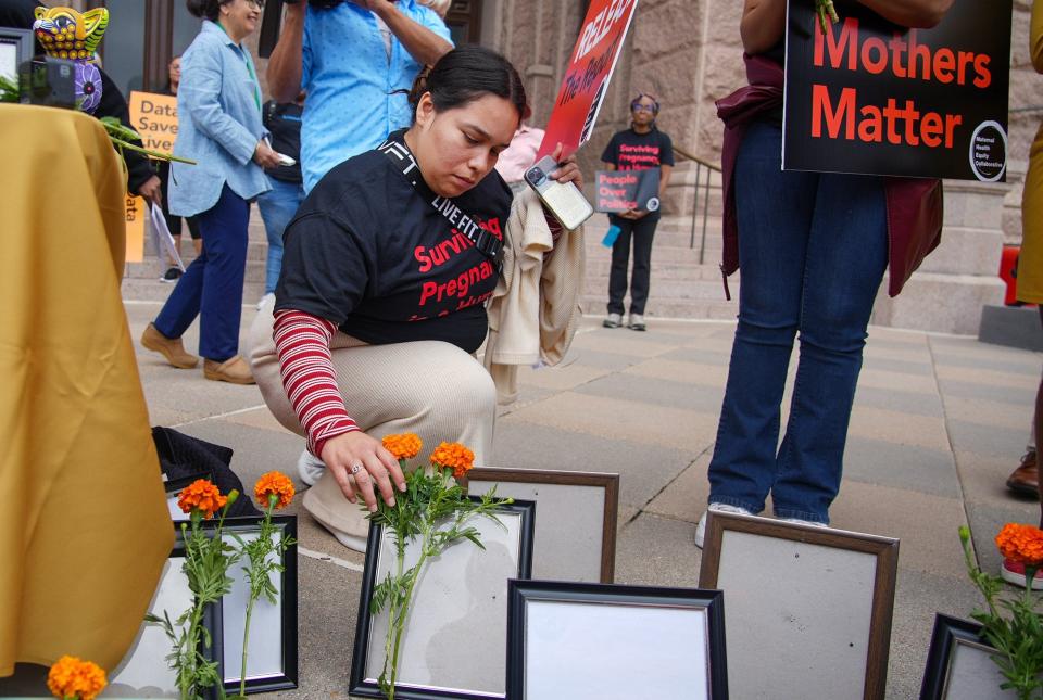 Jariza Marroquin places flowers at empty picture frames during a 2022 protest outside the Capitol to represent people who died during childbirth.