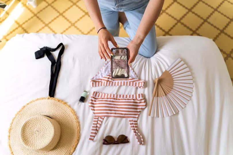 Woman takes photo of clothing on bed