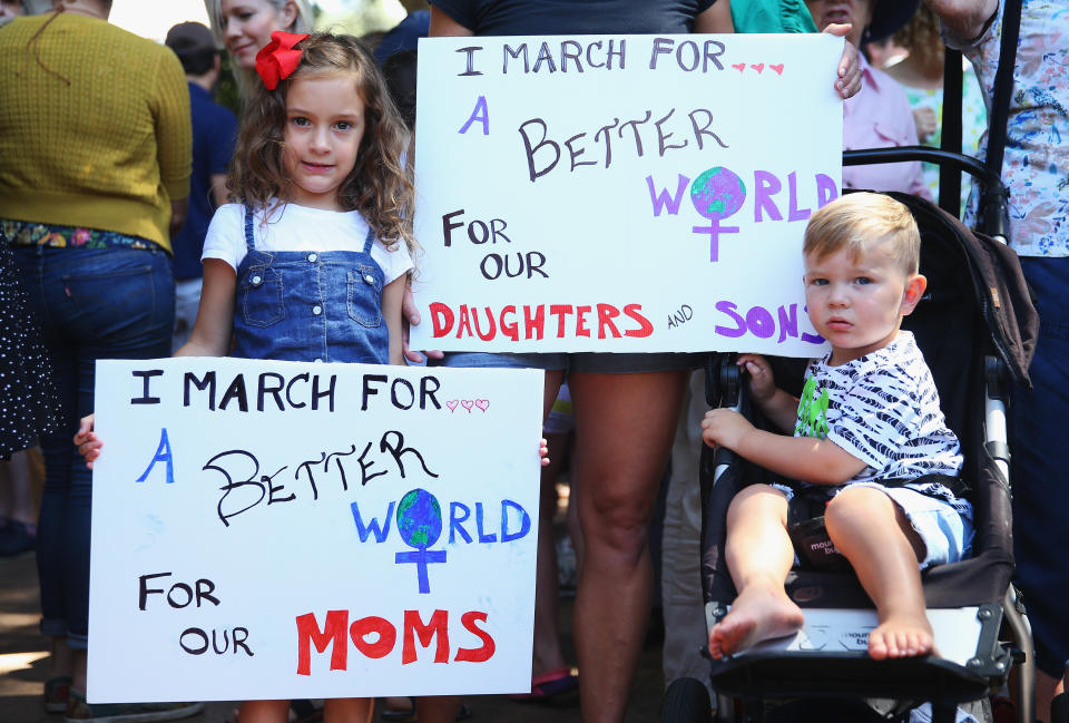 Emily Kafe and Lachlan Kafe hold banners as they stand beside their mother, Gwen Churnie (obscured) on January 21, 2017 in Sydney, Australia.&nbsp;