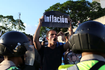 An opposition supporter holding a placard that reads, "Inflation", shouts slogans in front of the riot police during a protest in Caracas. REUTERS/Carlos Garcia Rawlins