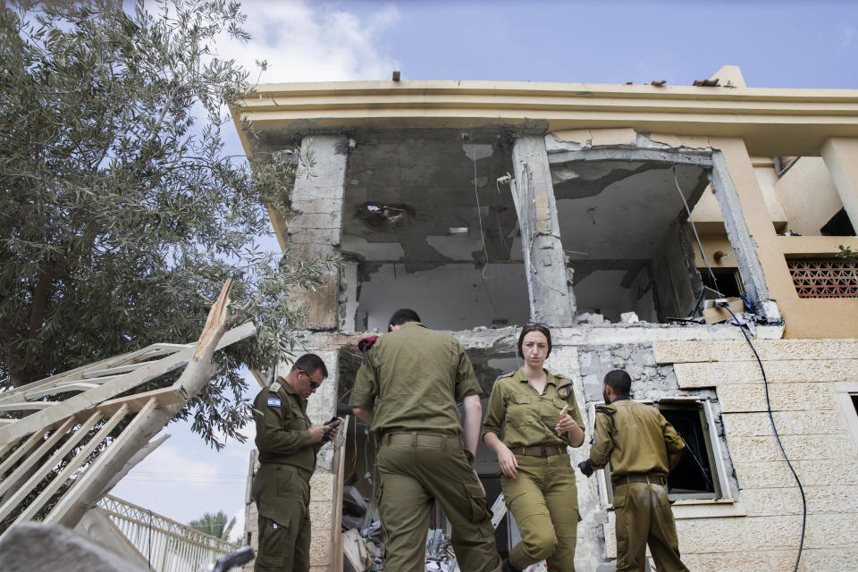 Israeli soldiers stand in front of a house that was hit by a missile fired from Gaza Strip, in the city of Beersheba, southern Israel, Wednesday, Oct. 17, 2018. A medical service said a woman and her three children, whose home was struck, were being treated for shock after they fled to their shelter upon being awoken by warning sirens. (AP Photo/Tsafrir Abayov)