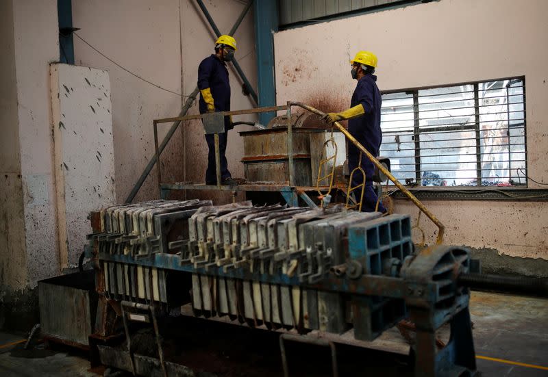 Workers stand next to a lead desulphurisation machine at ACE Green recycling Inc in Ghaziabad