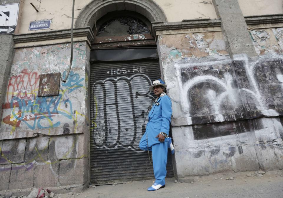 Jesus Gonzalez de la Rosa dressed in "Pachuco" style poses next to a wall with graffiti in Mexico City