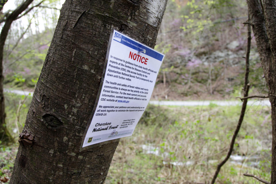 In this March 30, 2020, photo, a notice is nailed to a tree along a portion of the Appalachian Trail in Cosby, Tenn. Hikers have been asked to leave the trail immediately as trailheads continue to close due to the coronavirus outbreak. (AP Photo/Sarah Blake Morgan)