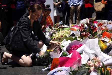A woman places a floral tribute amongst thousands of others near the cafe in central Sydney December 16, 2014 where hostages were held for over 16-hours.. REUTERS/David Gray