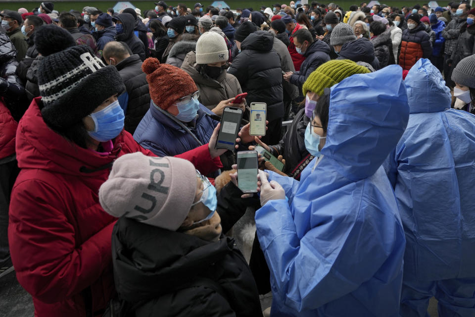 Volunteers help women enter information on their smartphones as others gather in line for mass coronavirus testing in Beijing, Monday, Jan. 24, 2022. Chinese authorities have lifted a monthlong lockdown of Xi'an and its 13 million residents as infections subside ahead of the Winter Olympics. Meanwhile, the 2 million residents of one Beijing district are being tested following a series of cases in the capital. (AP Photo/Andy Wong)